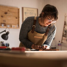 Eine Auszubildende arbeitet konzentriert an einem Werkstück in einer Werkstatt.