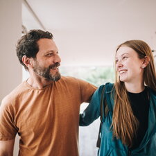 Eine erwachsene Person spricht unterstützend mit einer jungen Frau in einem hellen Innenraum.