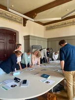 Beratende stehen an einem Tisch und haben Workshop-Material vor sich