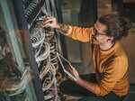Ein Mann arbeitet an einem Serverschrank, überprüft Kabelverbindungen und hält ein Tablet in der Hand.